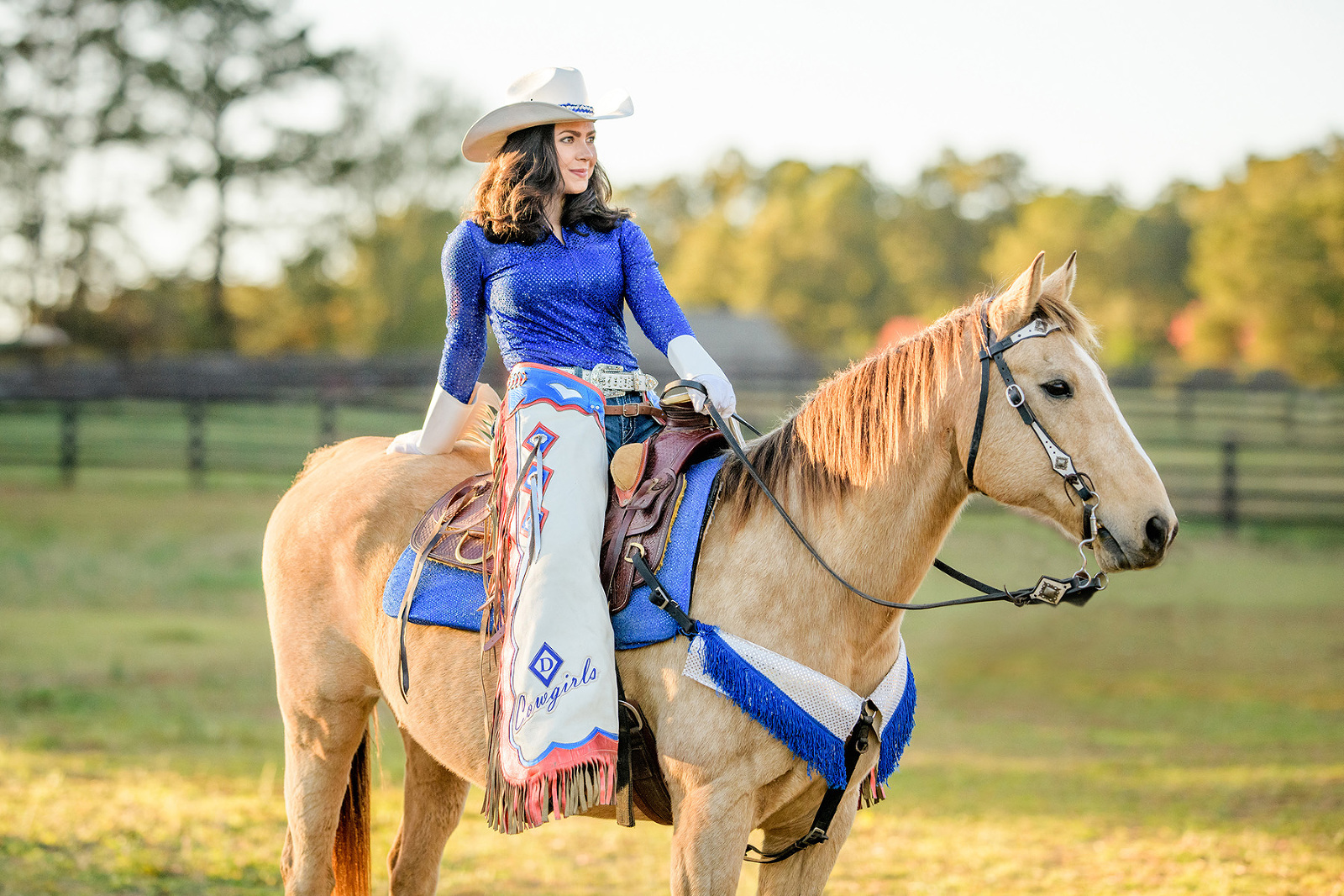 cowgirl sitting on her horse looking off into the sunset